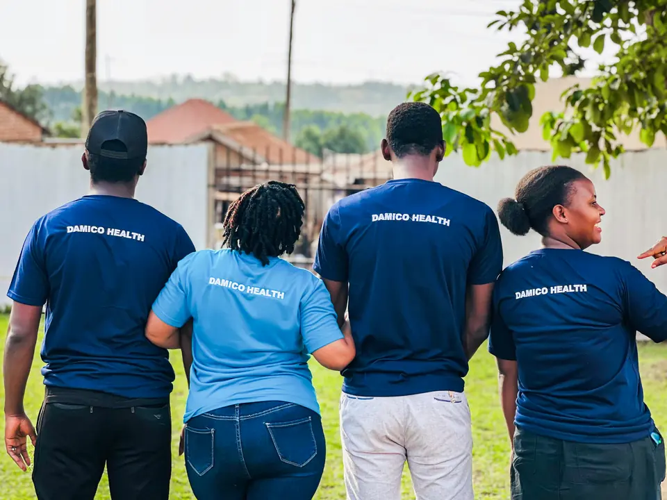 Four team members seen from behind, each wearing a shirt printed with Damico Health.