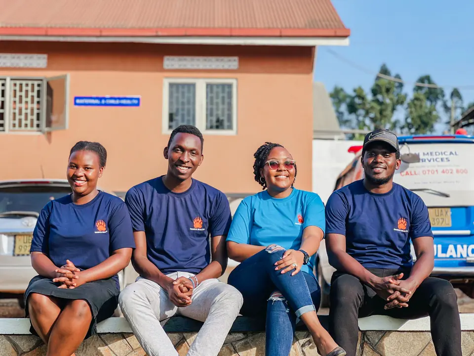 Four members of the Damico Health team sit together outside a maternal and child health building.